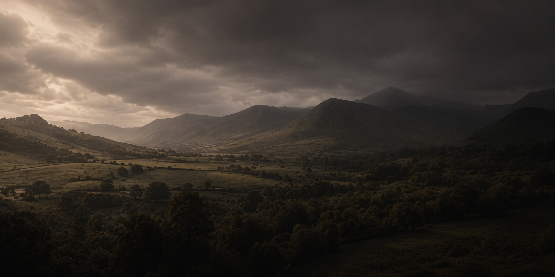 Dark moody landscape photograph of a valley with rolling hills, trees, and distant mountains under heavy storm clouds with light breaking through.